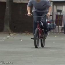 A guy rides along a curved railing on his BMX bike