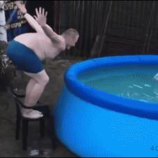 A man tries to dive off a chair into a pool.