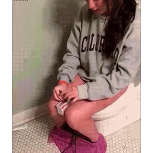 A girl tries a match trick while on the toilet