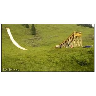 A man launches from a huge water slide into a small pool.