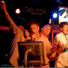 A drunk guy dances with a lighter during karaoke.