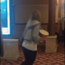 A clumsy girl spills all her popcorn while falling.
