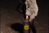 A girl sits on top of a bollard.