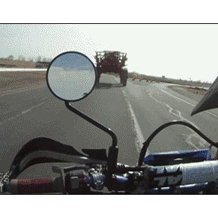 Motorcycle passes underneath tractor.