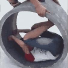 A kid attempts to roll inside a concrete pipe.