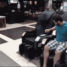 A troll pretends to get shocked by a massage chair to scare a girl.